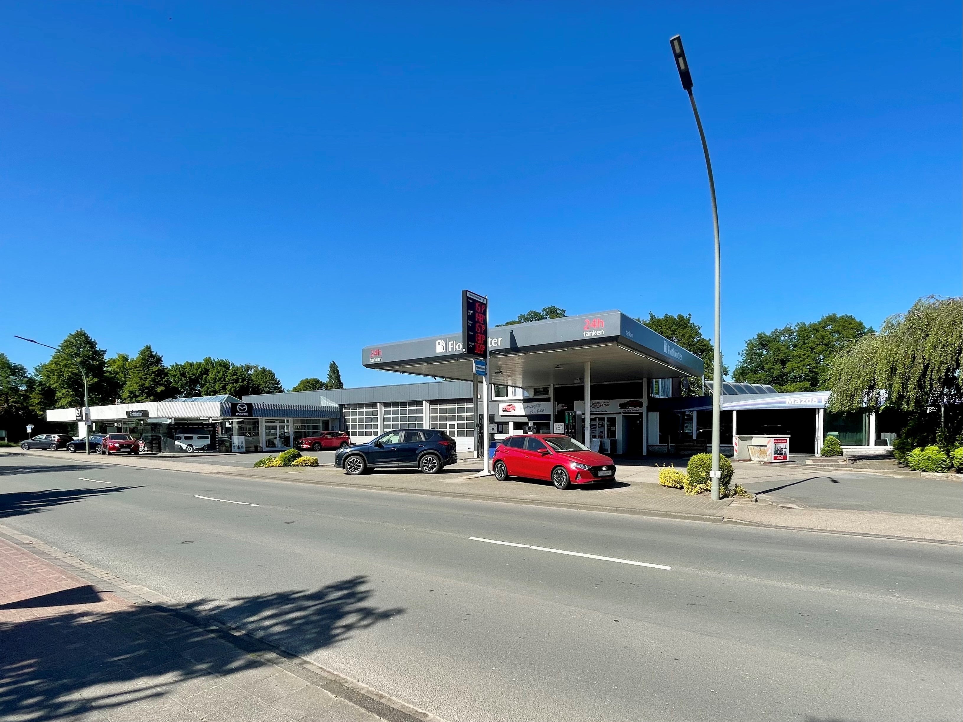 Eine Tankstelle, an der mehrere Autos stehen, mit einem klaren Himmel im Hintergrund.