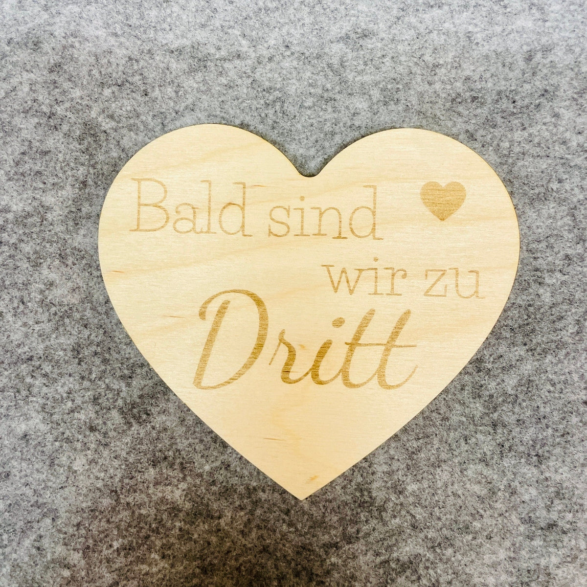 Herz aus Holz mit der aufschrift "Bald sind wir zu dritt" zum Scchwangerschaft mitteilen Schild Das Glückswerk