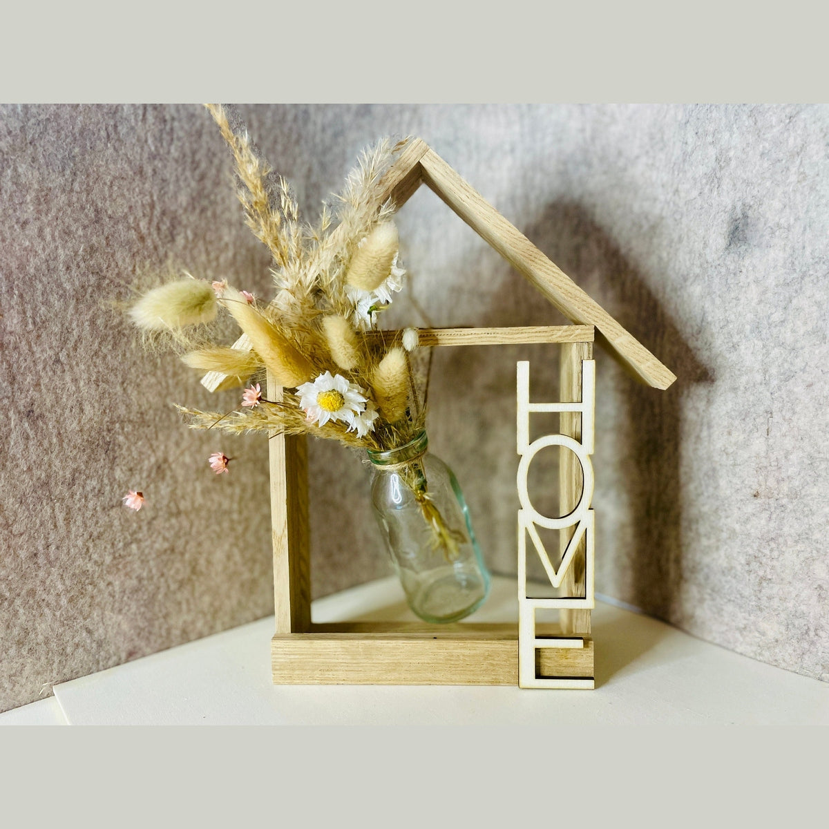 Holzhaus mit Glasvase und Trockenblumen und Aufschrift Home Dekoration Das Glückswerk
