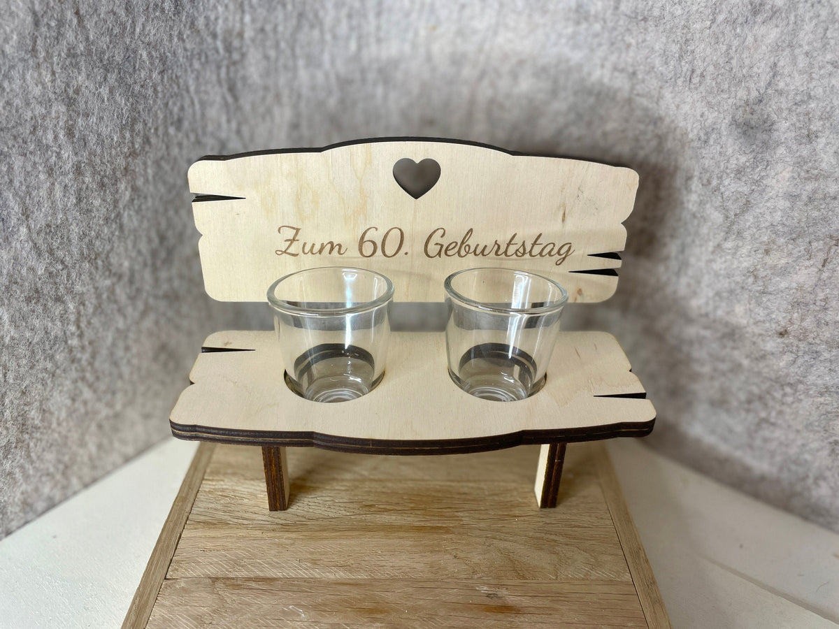 Holzbank mit Gravur „Zum 60. Geburtstag“ und zwei leeren Gläsern