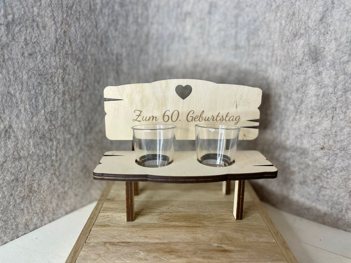 Holzbank „Zum 60. Geburtstag“ mit zwei Schnapsgläsern auf Holzboden