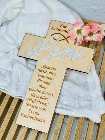 Taufkreuz mit Namensschild „Leon“ auf weißem Stoffuntergrund