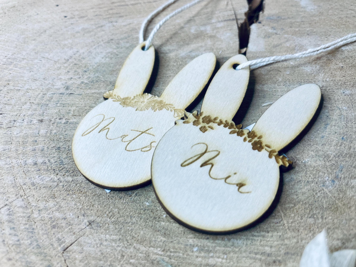 Nahaufnahme zweier Osterhasen-Anhänger aus Holz mit Blumenkranz-Gravur