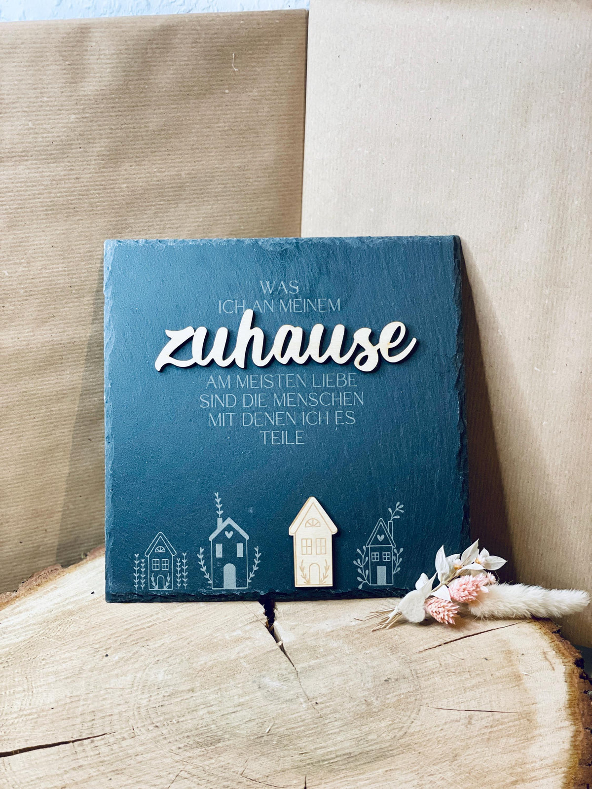 Schiefertafel Zuhause auf Holzscheibe vor beigem Stoffhintergrund