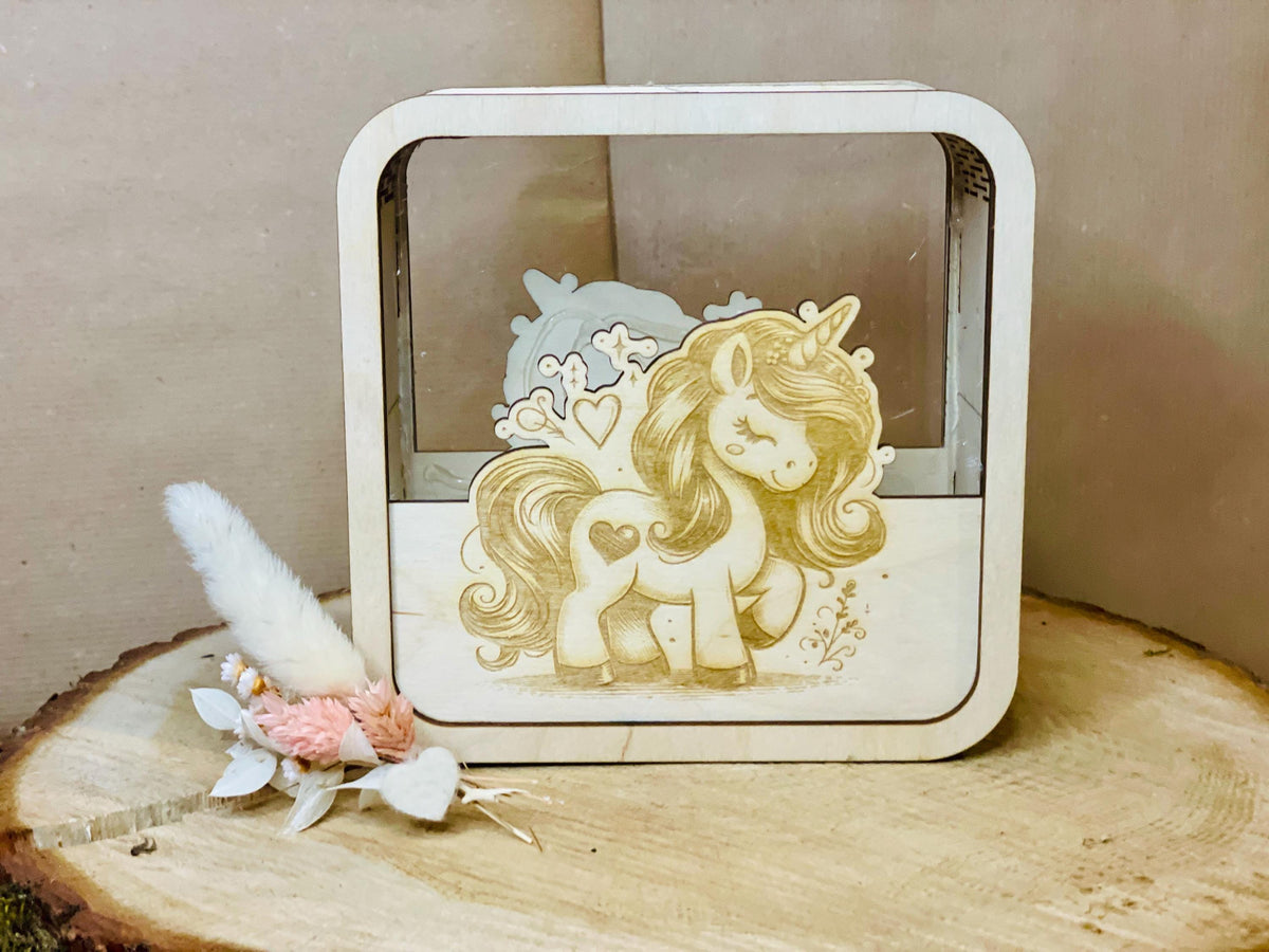 Holzspardose mit Einhorn-Motiv und Blumendekoration auf Holzstumpf