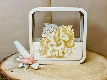 Holzspardose mit Einhorn-Motiv und Blumendekoration auf Holzstumpf