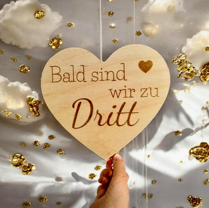 Herz aus Holz mit der aufschrift "Bald sind wir zu dritt" zum Scchwangerschaft mitteilen Schild Das Glückswerk