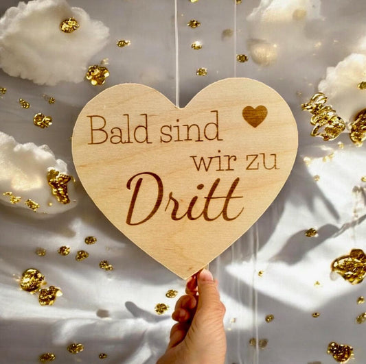 Herz aus Holz mit der aufschrift "Bald sind wir zu dritt" zum Scchwangerschaft mitteilen Schild Das Glückswerk
