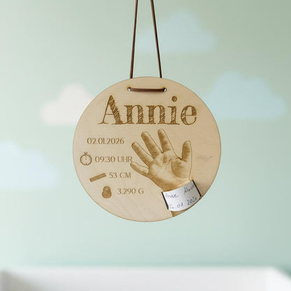 Geburtsarmband-Halter Holz mit Gravur „Annie“, hängend vor Wolkendeko